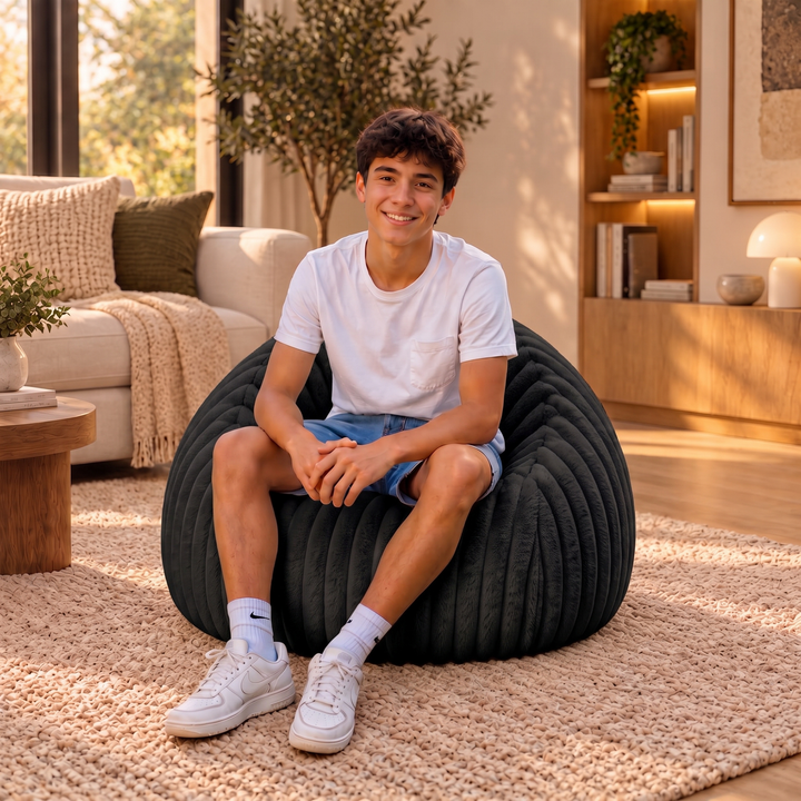 Personne assise confortablement dans un pouf poire en fourrure côtelée