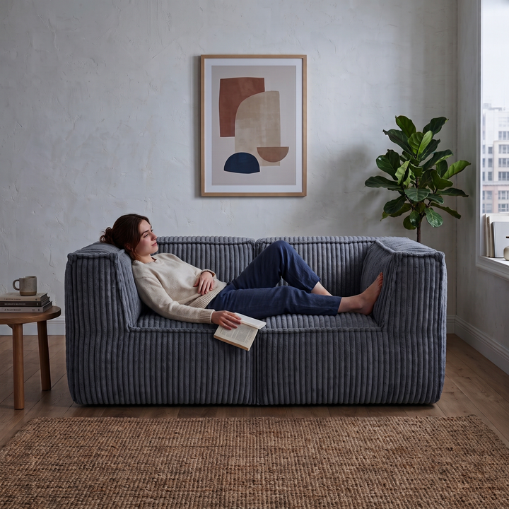 Personne allongée dans un canapé modulable2 places en velours côtelé gris foncé