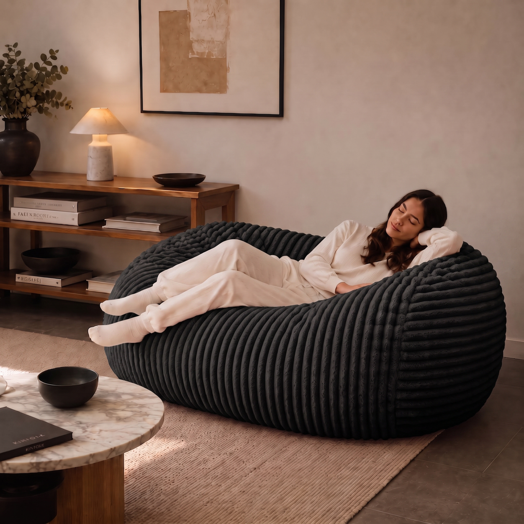 Personne allongée sur un pouf long géant déhoussable noir en fourrure côtelée dans un salon