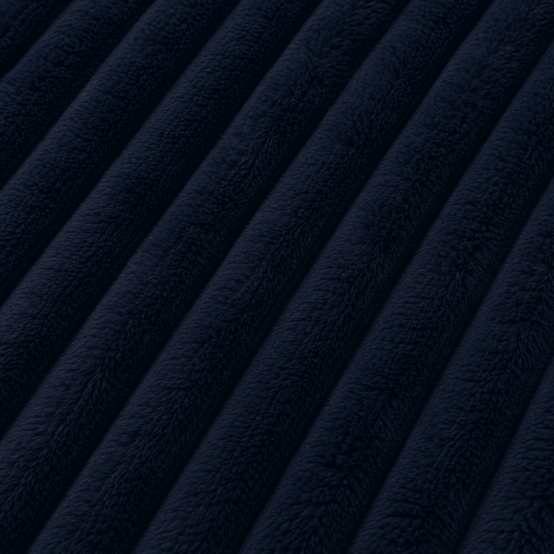 Fourrure côtelée bleu nuit : texture dense et moelleuse, lignes ondulées visibles.