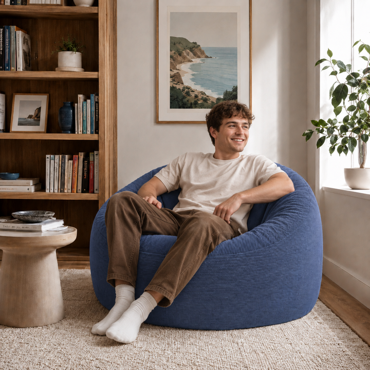 Personne assise sur un pouf déhoussable 100 cm en velours côtelé, dans un salon.